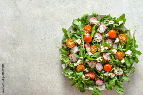 Healthy food. Vegetable salad with arugula, tomato, radish and seeds. Vegetarian meal on plate.