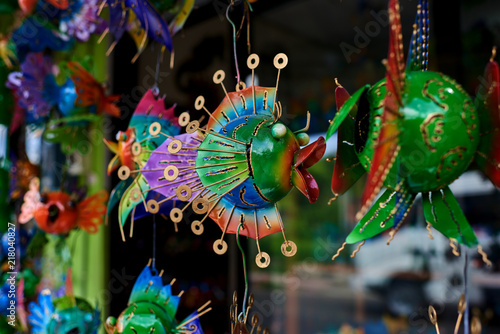 Colorful  souvenir background. Hanging decoration in the market. Handmade metallic fish hanging on the tourist market. Sale of souvenirs. Funny handmade fishes with bright colorful patterned.