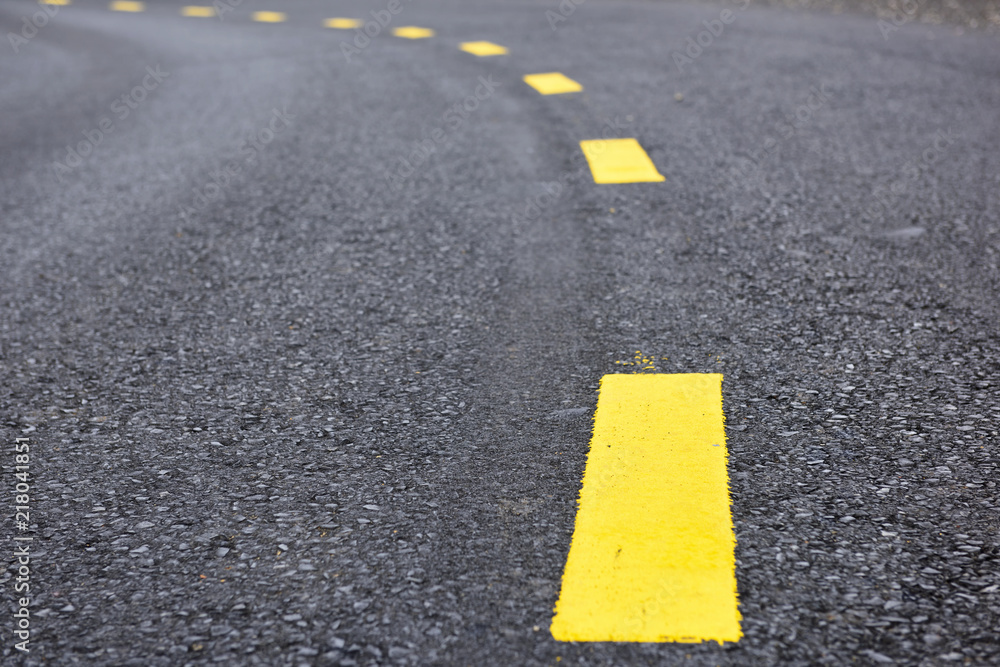 Closeup asphalt road with marking lines for giving directions, traffic lines concept Closeup asphalt road with marking lines for giving directions, traffic lines concept