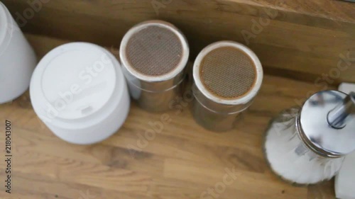 Coffee supplies wooden sticks for mixing coffee, plastic cups, sugar bowl, plastic tubes, paper napkins, cinnamon, on the table. Side view, indoor, real time, natural light, day, right to left movemen