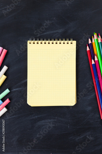 Back To School concept. School supplies on blackboard background, accessories for the schoolroom - pencils, notebooks, scissors, chalk, markers.