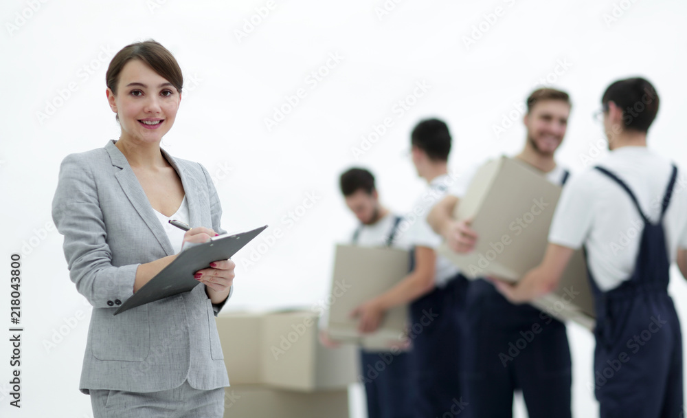 Woman manager holding clipboard on blurred background with mover Woman manager holding clipboard on blurred background with mover