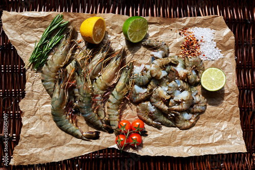 Shrimp are on the light brown parchment paper cut to close the two halves of lime and lemon