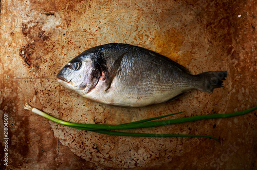 Fototapeta Naklejka Na Ścianę i Meble -  Flavored with fresh sea bass lying on a baking sheet for baking
