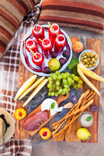 Picnic on the beach at sunset in the style of boho. Concept outdoors evening healthy dinnner with fruit and juice