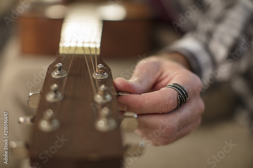 Close-up of man's hand tuning guitar photo