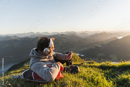 Hiker lying in grass, taking a break and listening music with headphones