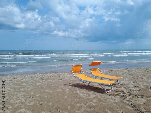 Vacanze al mare. Lettini prendi sole sulla riva sabbiosa di Rimini