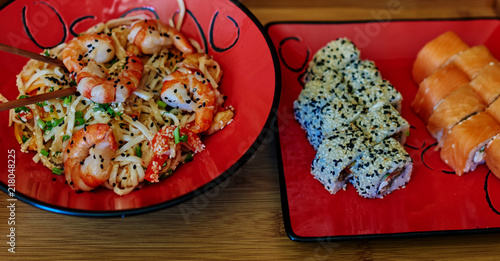 Cook has prepared two servings of sushi, one with salmon cucumber and cheese filadelfiya second with smoked eel served everything on the red plate to the Japanese style photo