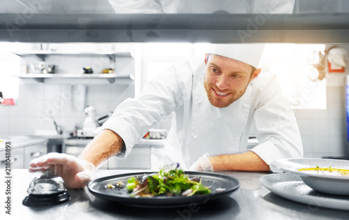 food cooking, profession and people concept - happy male chef cook with plate of soup and salad ringing bell at restaurant kitchen table
