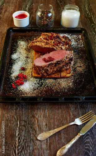 The trendy expensive steakhouse chef prepared a piece of pork tenderloin in the oven, the meat turned out medium rare places with blood for gourmets, the meat will cook the sauce of red berries