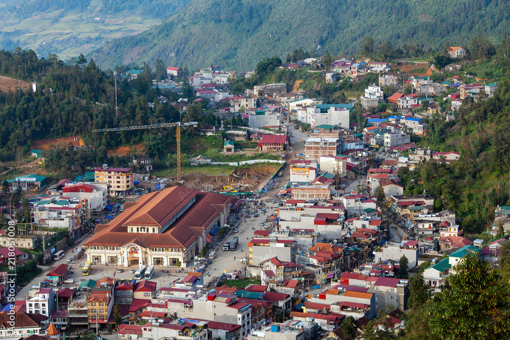 Aerial view of clusters of buildings nestled in the green valley of Sapa, Vietnam