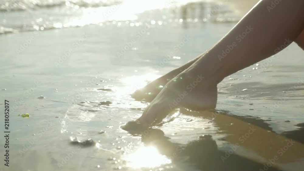 Tanned legs of a young girl splashing into the sea, close-up. Bokeh and sunlight Tanned legs of a young girl splashing into the sea, close-up. Bokeh and sunlight