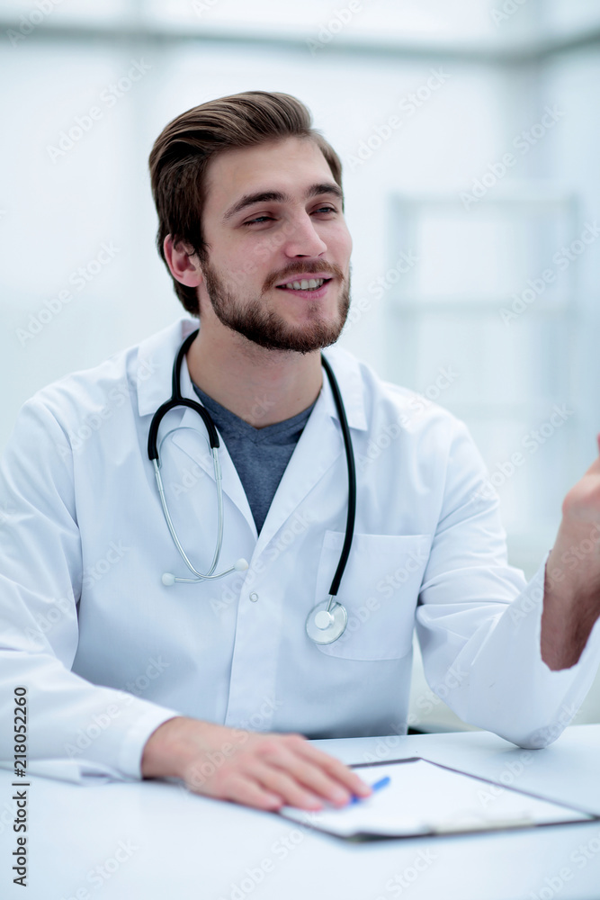 smiling doctor sitting behind a Desk smiling doctor sitting behind a Desk