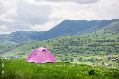 Tent is built in meadow. Beautiful, fresh morning in mountain landscape next to medieval village. Concept of freedom, camping and travelling around the world. Picnic in nature 