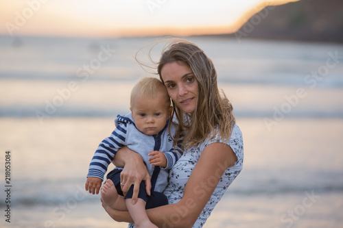 Young mother with her beautiful children, enjoying the sunset over the ocean on a low tide in Devon