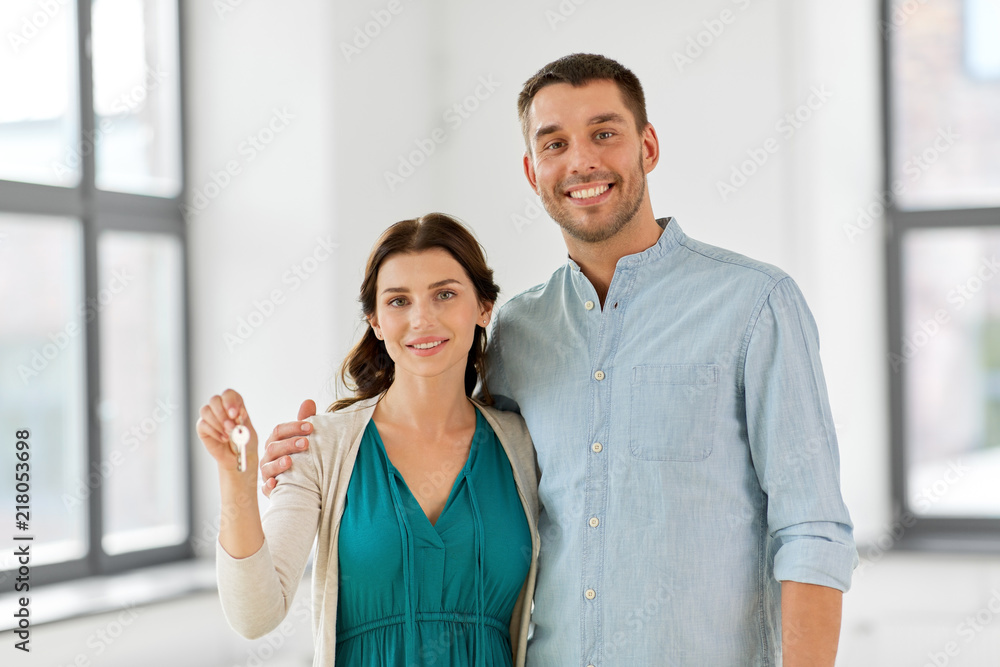 mortgage, people and real estate concept - happy couple with keys at empty room of new home