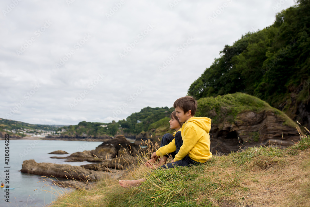 Children, enjoying quiet cloudy day on the ocean shore on the cliff, rocky beach