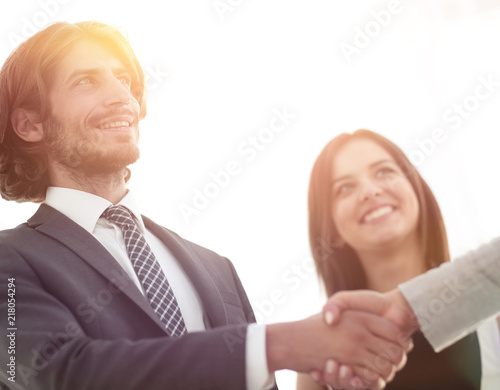 Businesspeople shaking hands against room with large window loo