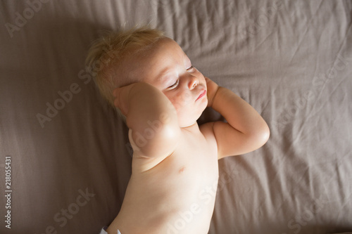 Portrait of a crawling baby on the bed in her room  Adorable baby boy in white sunny bedroom  Newborn child relaxing in bed