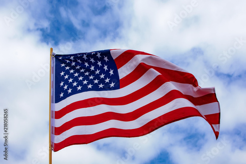 USA Flagge weht im Wind bei leicht bewölktem blauen Himmel