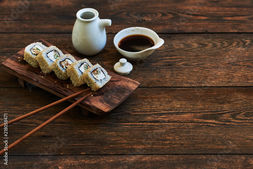 Sushi roll with salmon, eel, calf caviar and cheese. Sushi menu. Japanese food. Sushi on dark background. Japanese cuisine, sushi set: sushi and sushi rolls on wooden plate, selective focus.