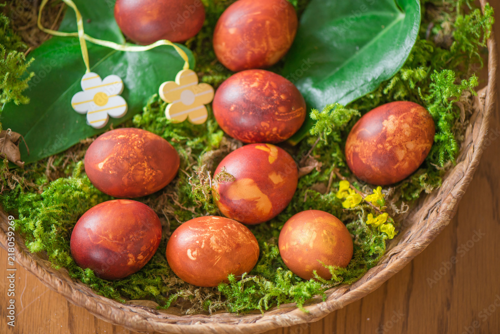 Easter eggs decorated with natural fresh leaves and boiled in onions peels, laying in wicker basket full of grass and thuja branches. dyeing eggs in the morning and celebrating Easter with family
