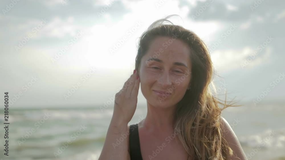 Portrait of a girl with freckles and pigmentation on her face smiling and posing for the camera, she stands on the beach against the sea Portrait of a girl with freckles and pigmentation on her face smiling and posing for the camera, she stands on the beach against the sea