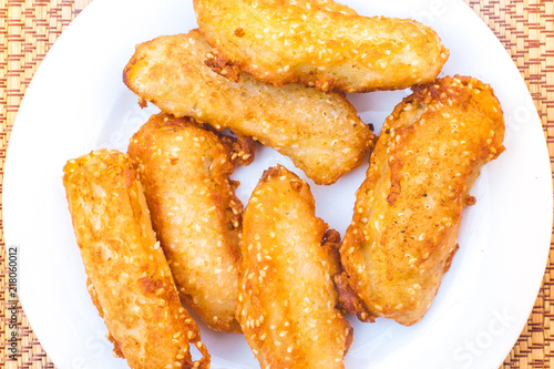 Thai banana fritters with sesame seeds (kloy kaak) on a white plate