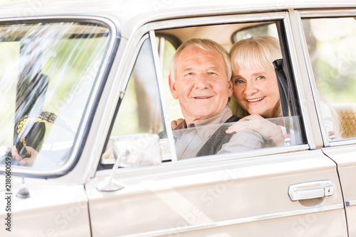 attractive senior woman hugging man in vintage car
