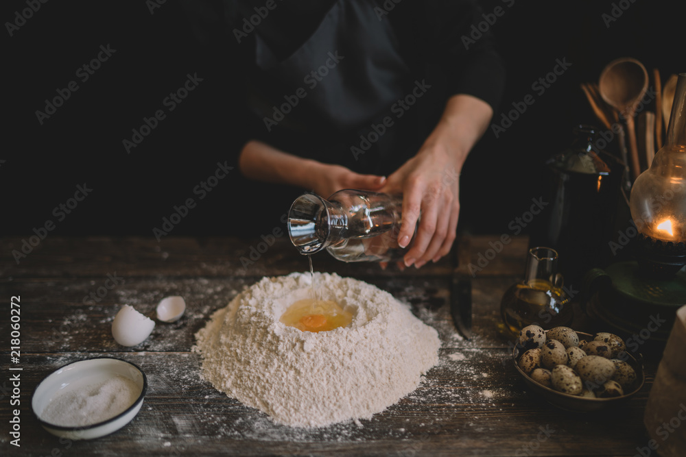 Food, cooking and baking concept. Making dough by female hands at bakery. Dough background. Preparation of the dough from fresh ingredients. On a rustic background. Ingredients for homemade baking.