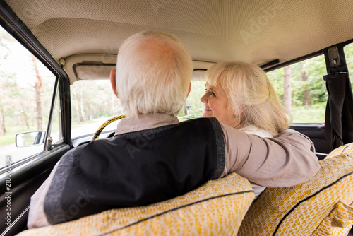 back view of senior husband and wife in beige car