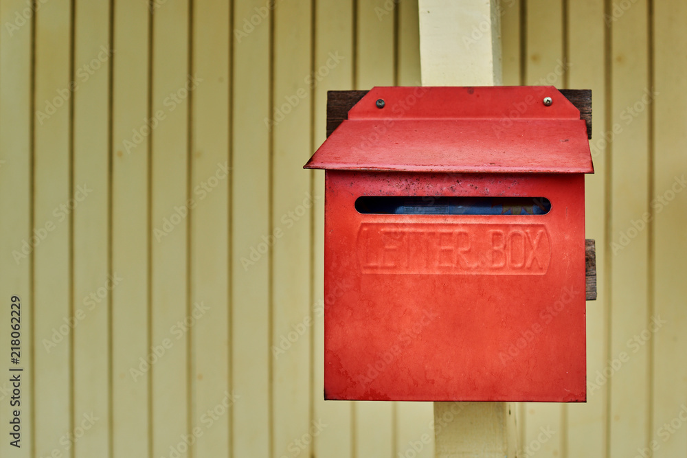 Old red mailbox on light yellow wooden wall background. Old red mailbox on light yellow wooden wall background.