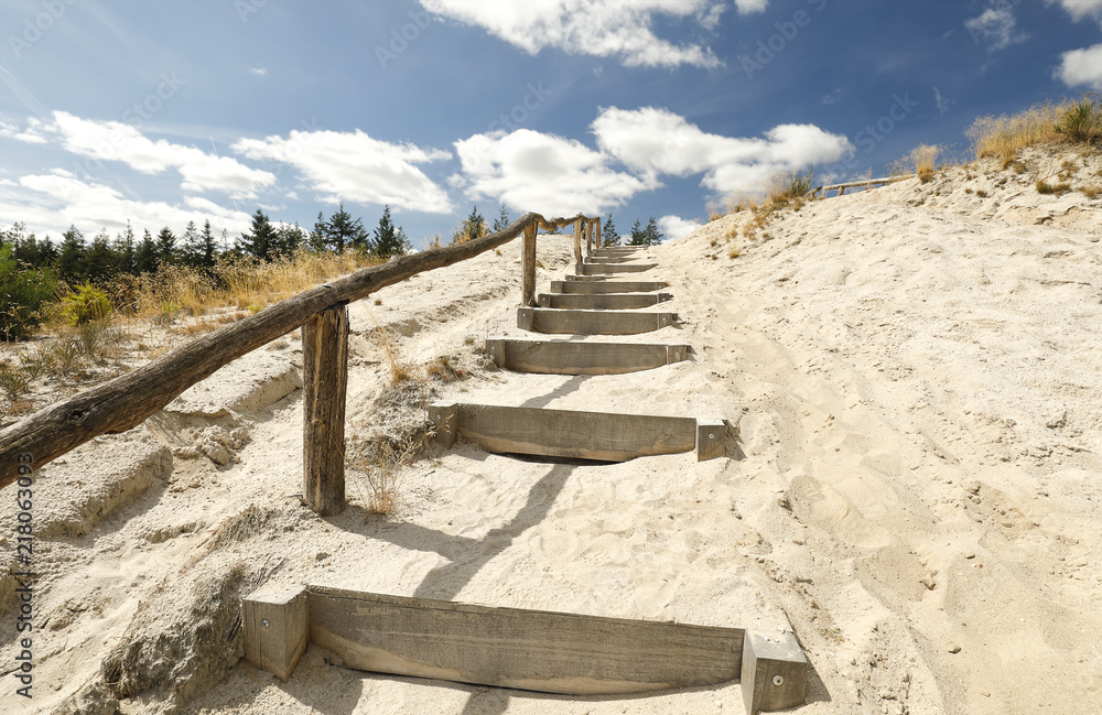 stairs on sand to blue sky with clouds