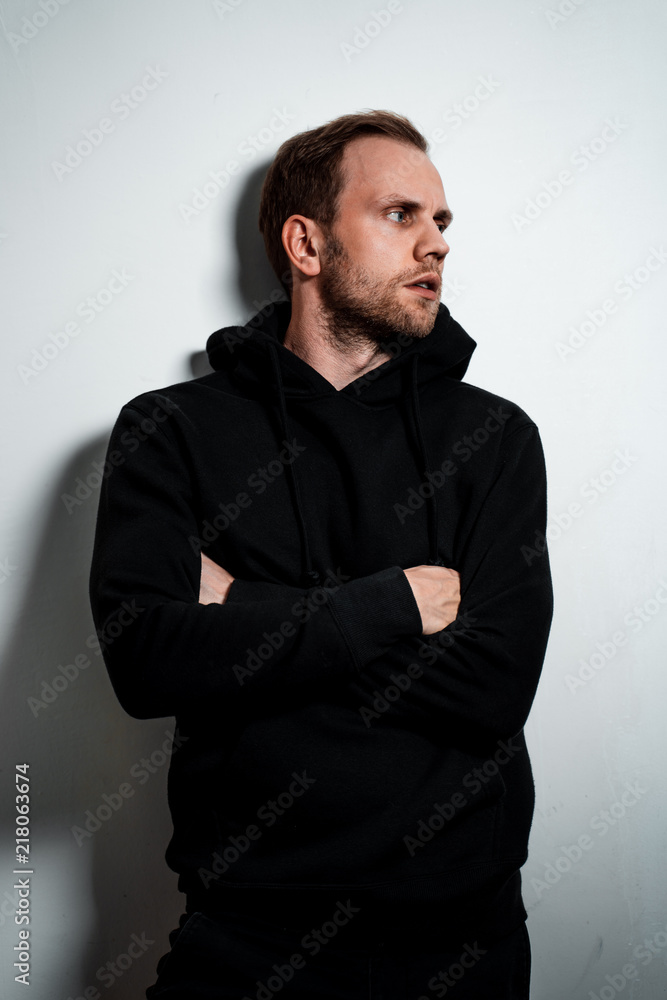 Man in a black sweater on a white wall background Man in a black sweater on a white wall background
