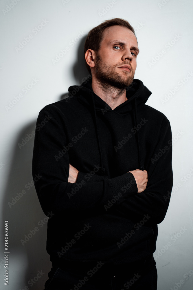 Man in a black sweater on a white wall background Man in a black sweater on a white wall background