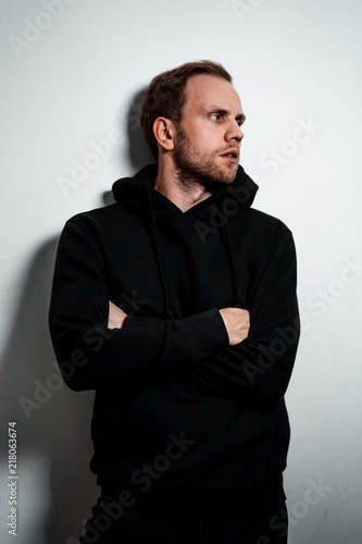 Man in a black sweater on a white wall background photo