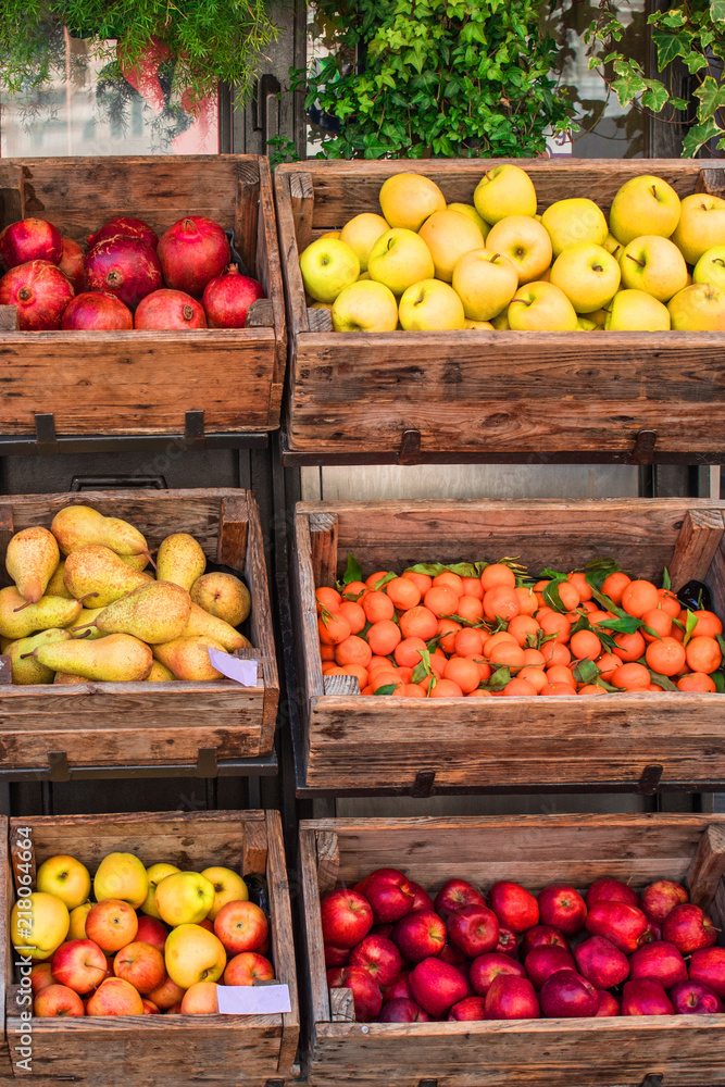 Assortment of fresh fruits and vegetables on market counter in a  wooden boxes