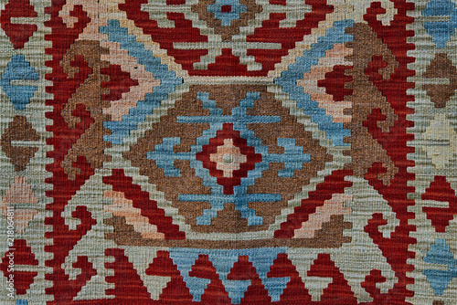 Close up of geometric patterned carpet. Hand woven rug with red, yellow, blue and other colors. Hand woven carpet with abstract design. Colorful carpet. Textile background. Abstract background.
