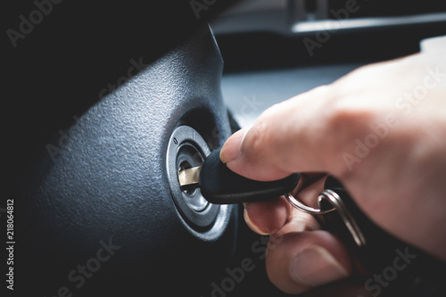 Hand turning car key in the key hole to start the car engine
