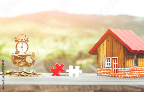 coins stacks and wooden house and piece jigsaw puzzle on desk, Property investment and house mortgage financial concept photo