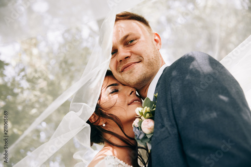 Fotografía Bride and groom in a park kissing