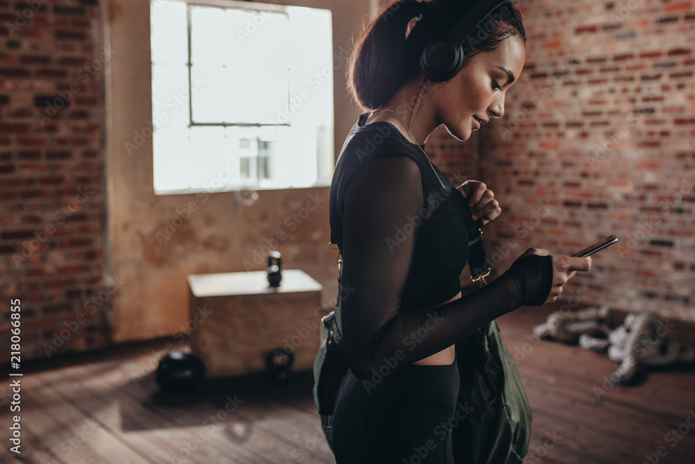 Naklejka premium Fitness woman at gym with phone