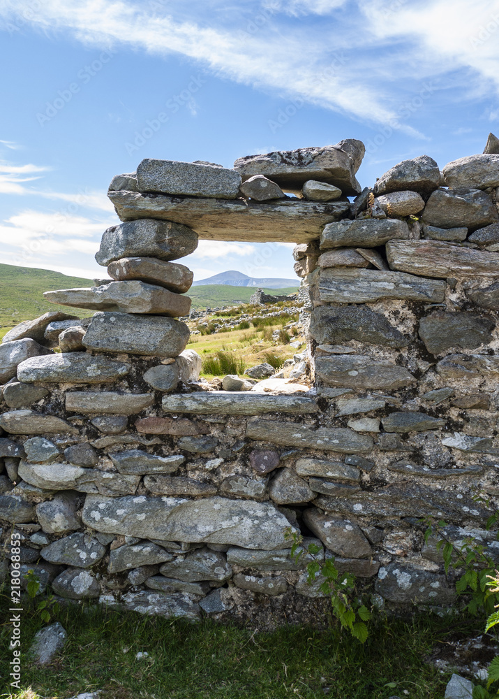 Ancient abandoned cottage, with views of tall hills through the window. Taken on Achill Island, Ireland