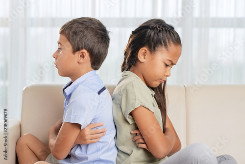 Tableau sur toile Side view of Asian brother and sister sitting on comfortable sofa in living room