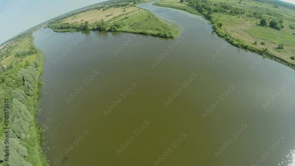 Quadrocopter, flies over the river enveloping a small island. There are many trees along the river. Summer sunny day. Video shooting from a bird's-eye view. Forest, river, in the distance can be seen Quadrocopter, flies over the river enveloping a small island. There are many trees along the river. Summer sunny day. Video shooting from a bird's-eye view. Forest, river, in the distance can be seen