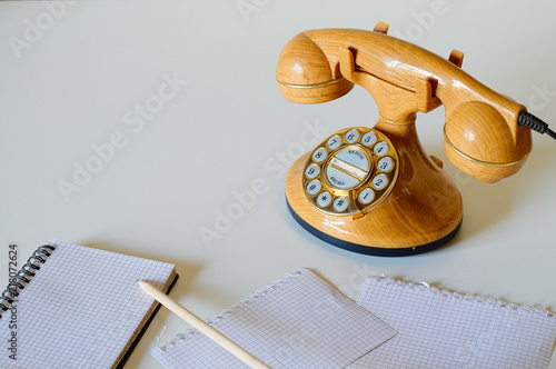 Old style phone in plastic like wood and golden dial with pencil and notebook