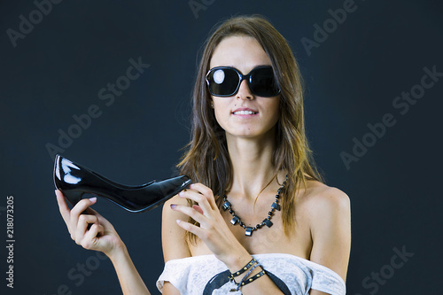 cute stylish brunette girl holding a shoe on a black background