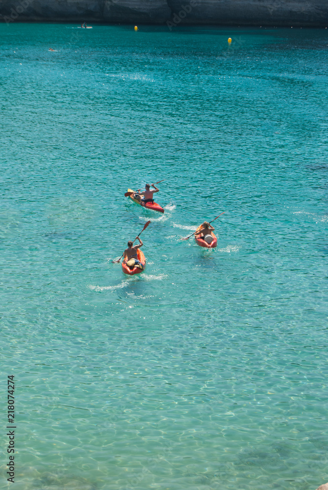 Three friends on a red kayaks in the sea
