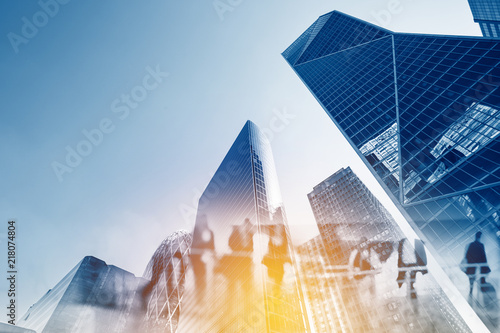 Silhouettes of people walking in the street near skyscrapers and modern office buildings in Paris business district. Multiple exposure blurred image. Economy, finances, business concept illustration
